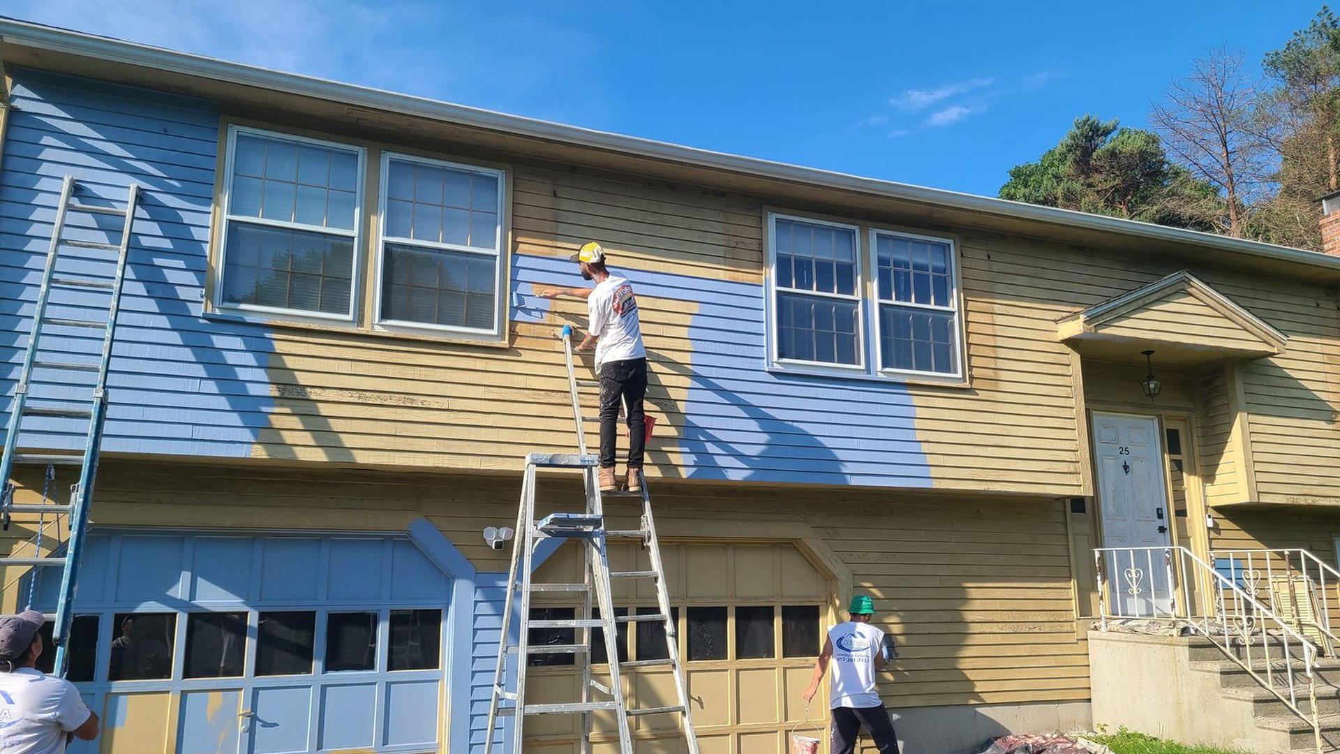 Aura Painting Inc crew repainting a Massachusetts home exterior, original colour still visible