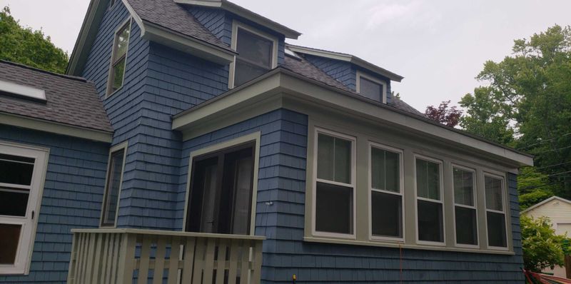 Blue shingle house with sage trim after exterior work