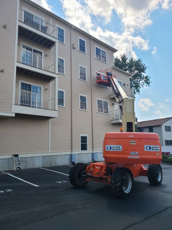 Boom lift staged to paint a four-storey apartment building