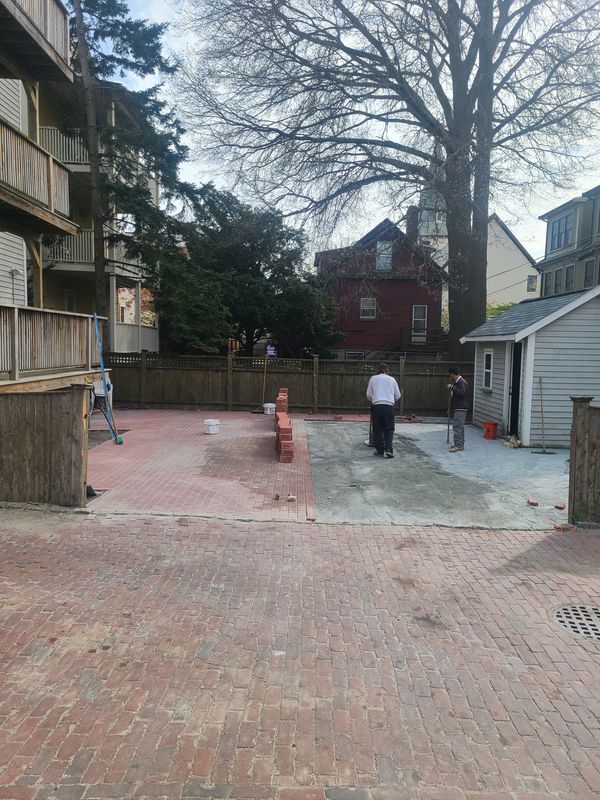 Crew laying brick borders on a patio installation