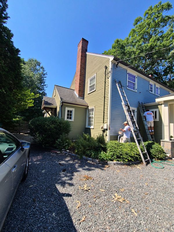 Two crew members working ladders on a colonial exterior