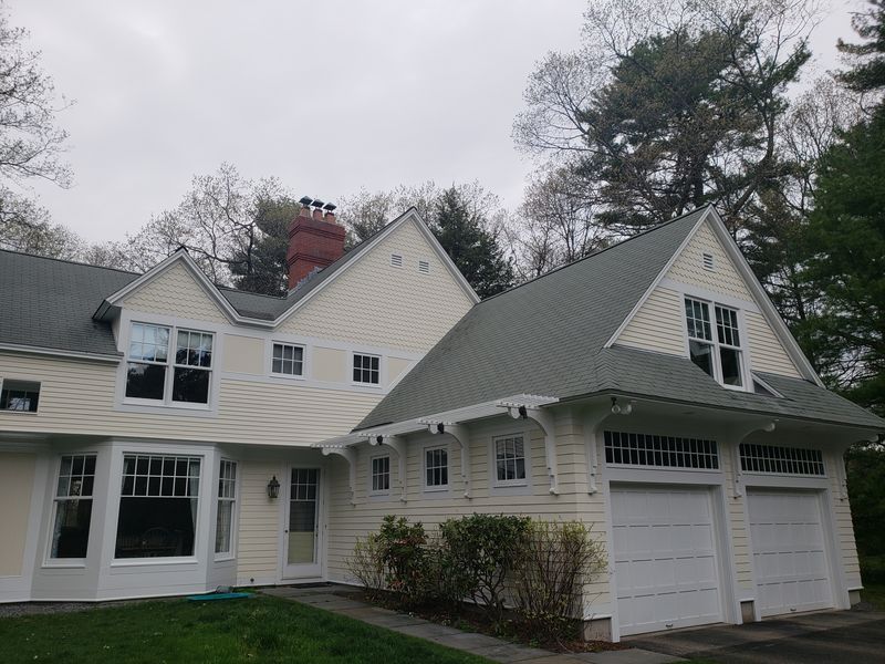 Pergola over garage bays on a large repainted home