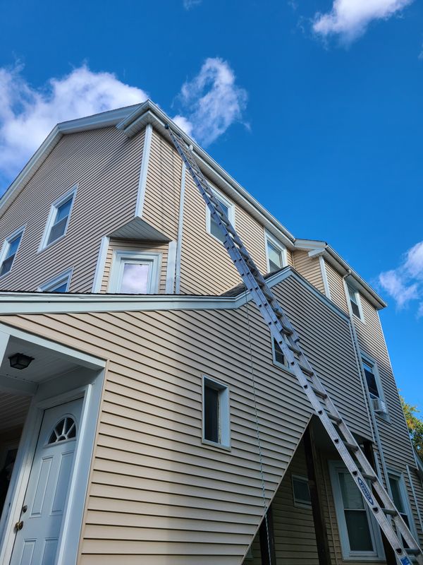 Extension ladder staged against a three-storey exterior in Greater Boston