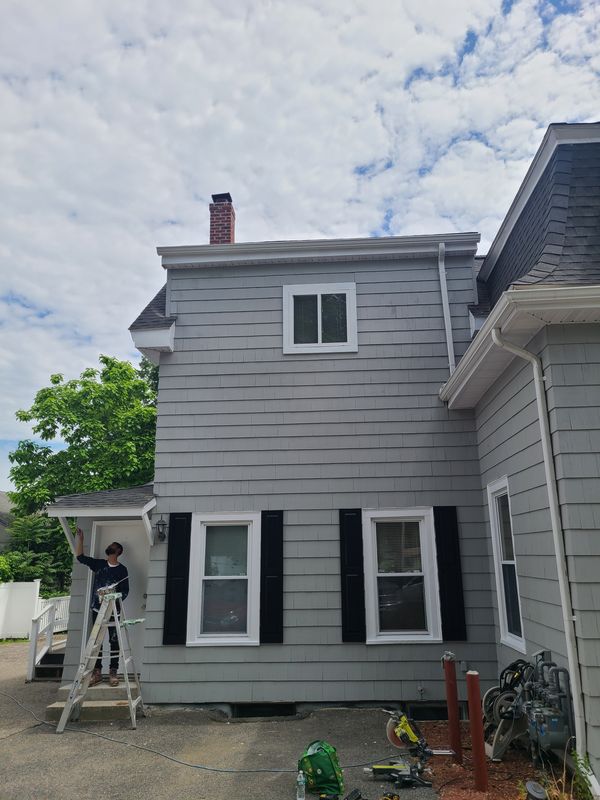 Crew working a grey gambrel Dutch colonial exterior