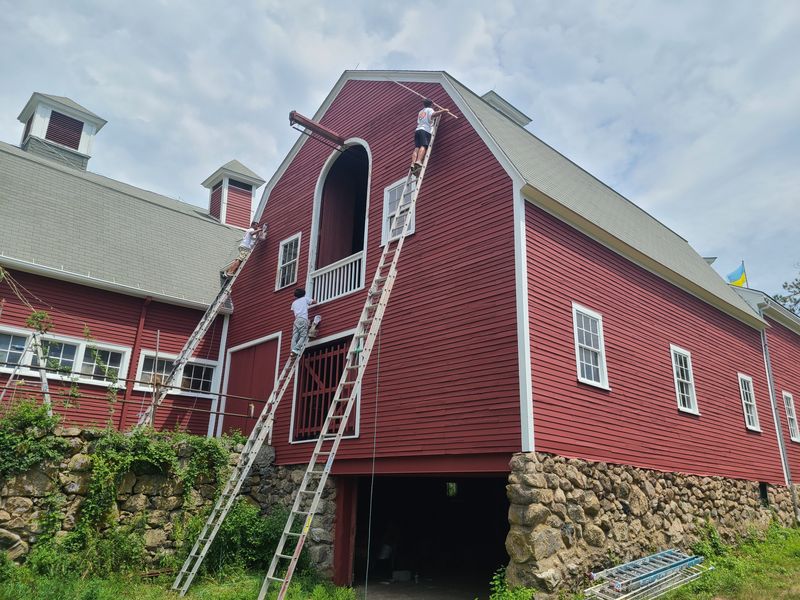 Aura Painting crew restoring a historic gambrel barn from extension ladders