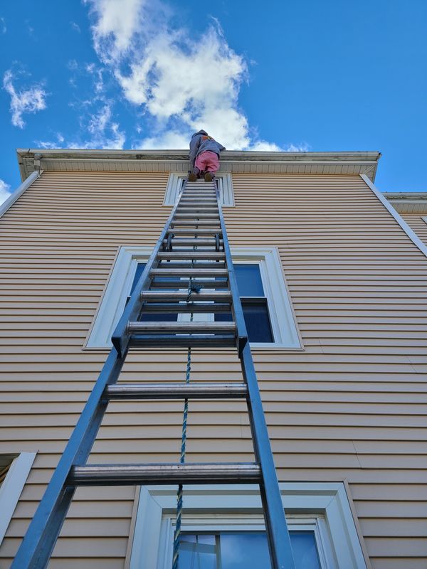 Extension ladder to a third-floor elevation on a Greater Boston multi-family