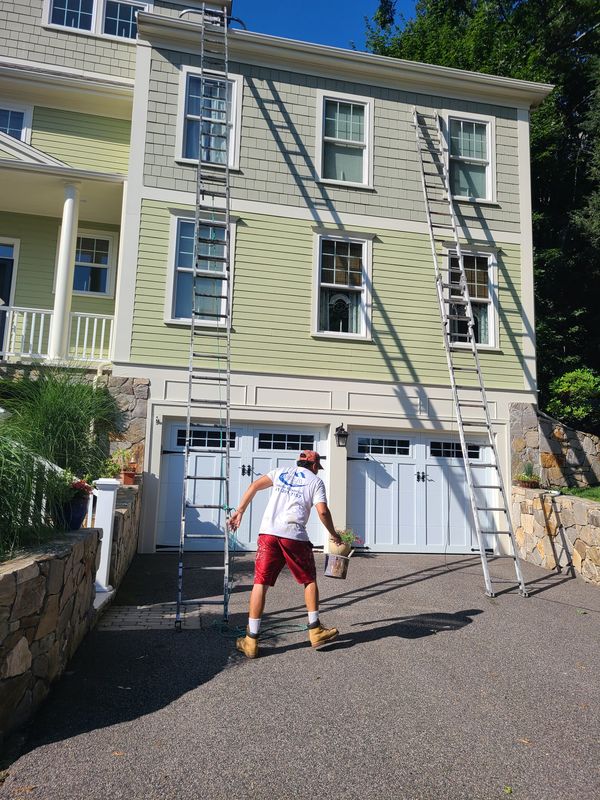 Crew member on a ladder during a large exterior repaint