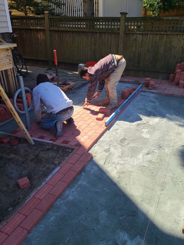 Crew setting brick border on a hardscape installation