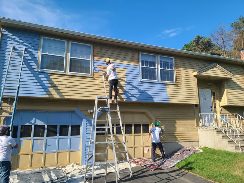 Crew repainting a raised ranch, original colour still visible