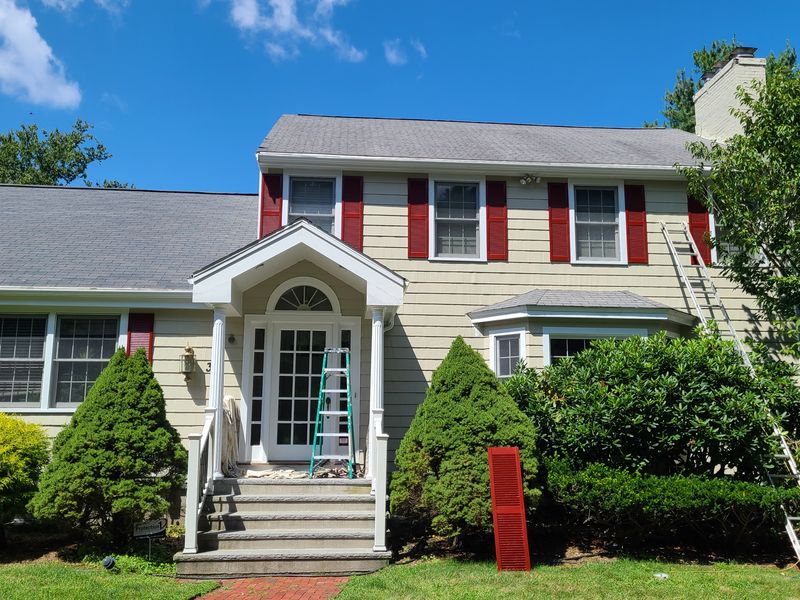Tan colonial with red shutters after exterior repainting