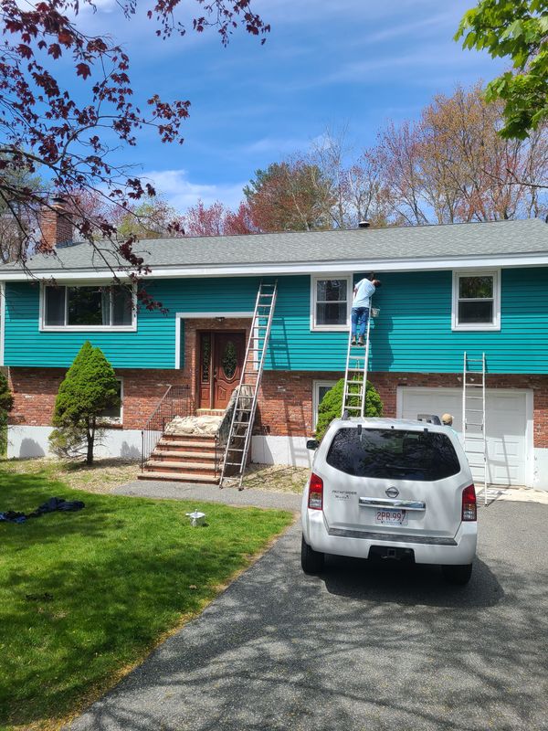 Raised ranch repainted in teal with ladders staged
