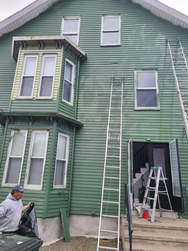 Three-family exterior mid-repaint with ladders staged