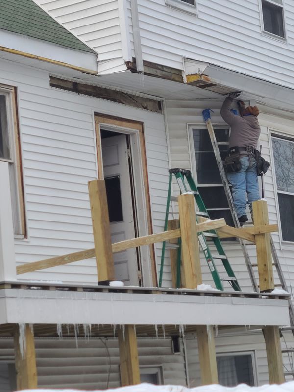 Window trim carpentry from staging on a multi-family exterior